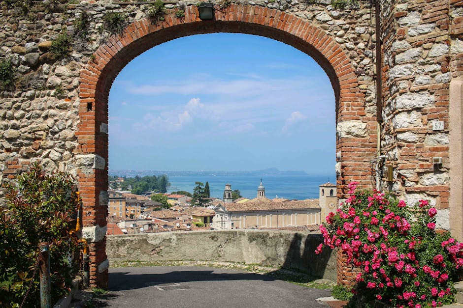 Charming view through an ancient archway overlooking a picturesque Italian town and lake.