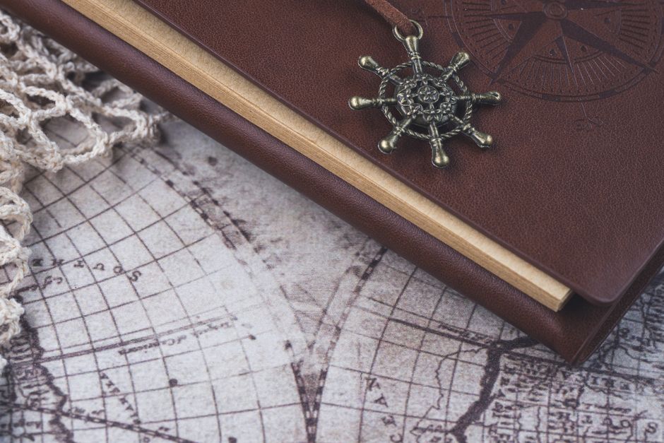A vintage-style leather-bound journal with a nautical charm on an antique world map, evoking exploration.